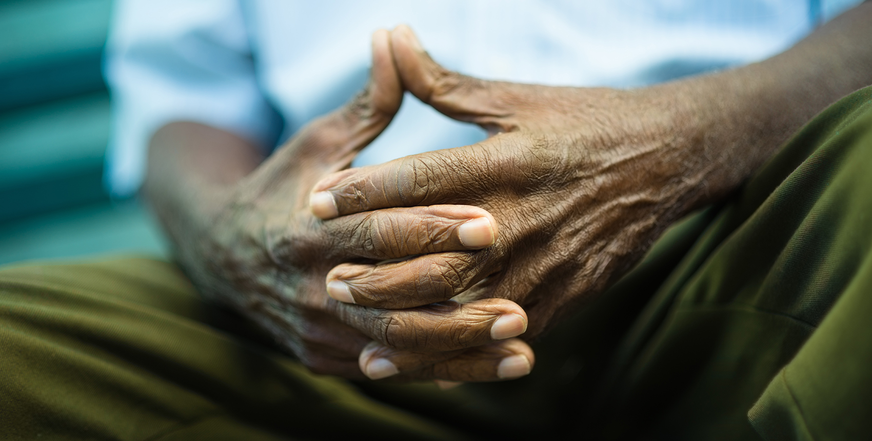 Closeup of hands of elderly Black man sitting on bench