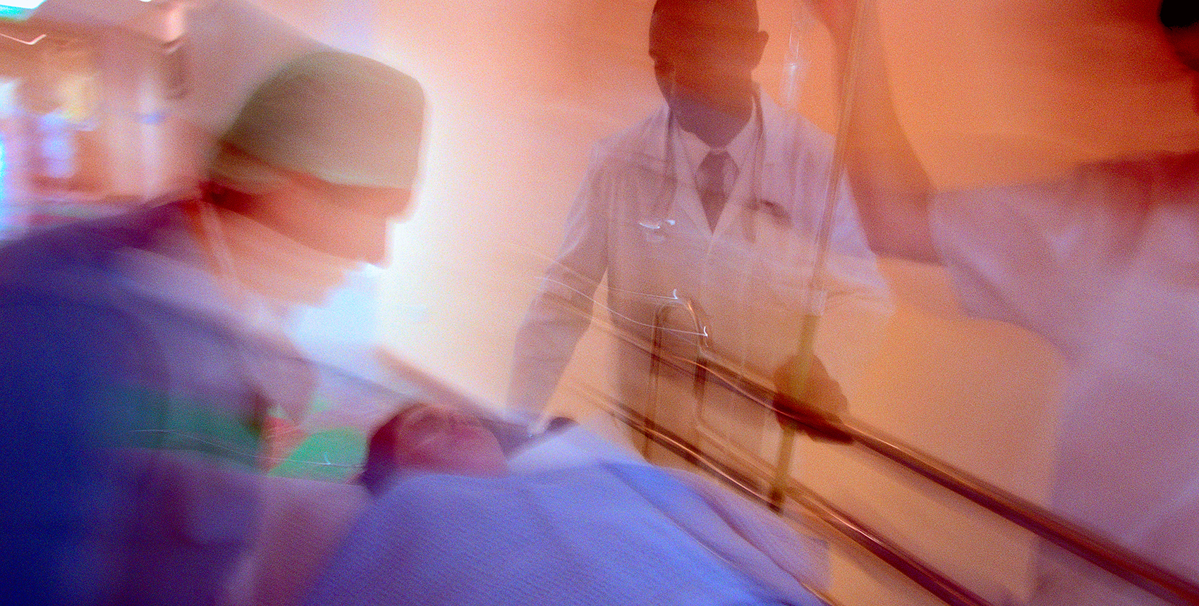 Motion blurred photo of hospital staff wheeling a patient on a gurney down a corridor