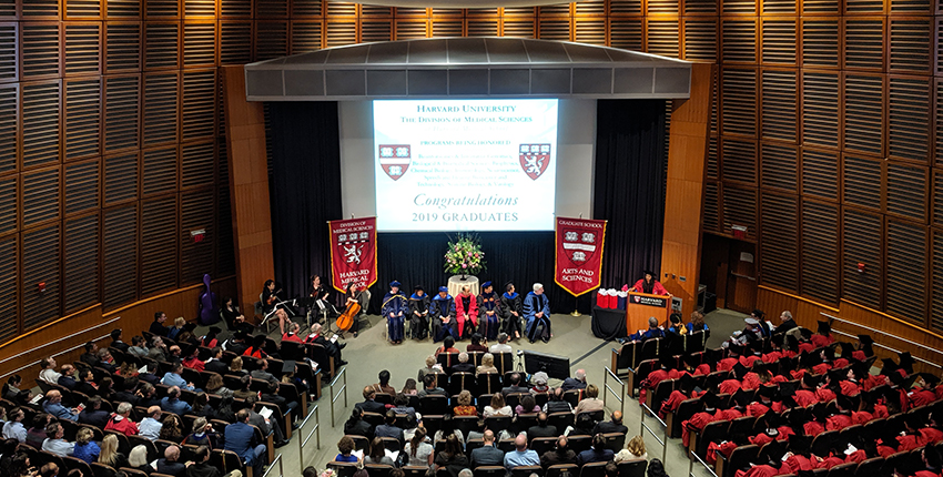 Auditorium with banners, program heads, graduates and guests