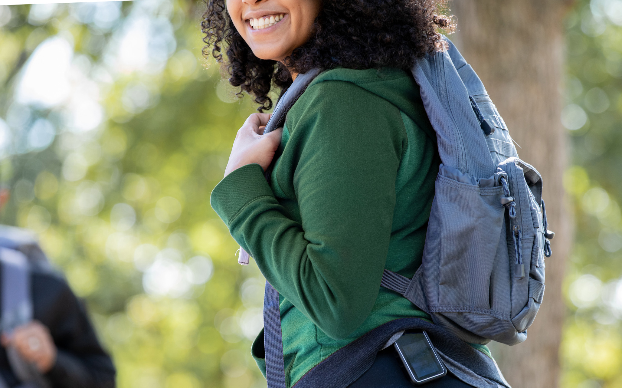 Young woman outdoors with backpack wearing a glucose monitor