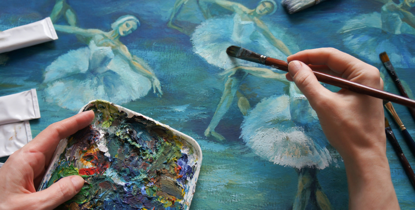 Close-up of a painter's hands working on a picture of dancers.