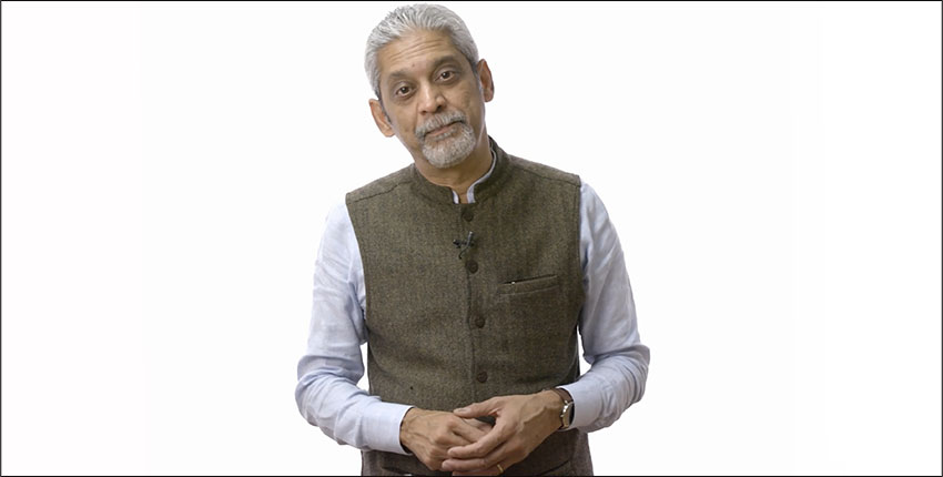 Gray-haired South Asian man in a vest and dress shirt