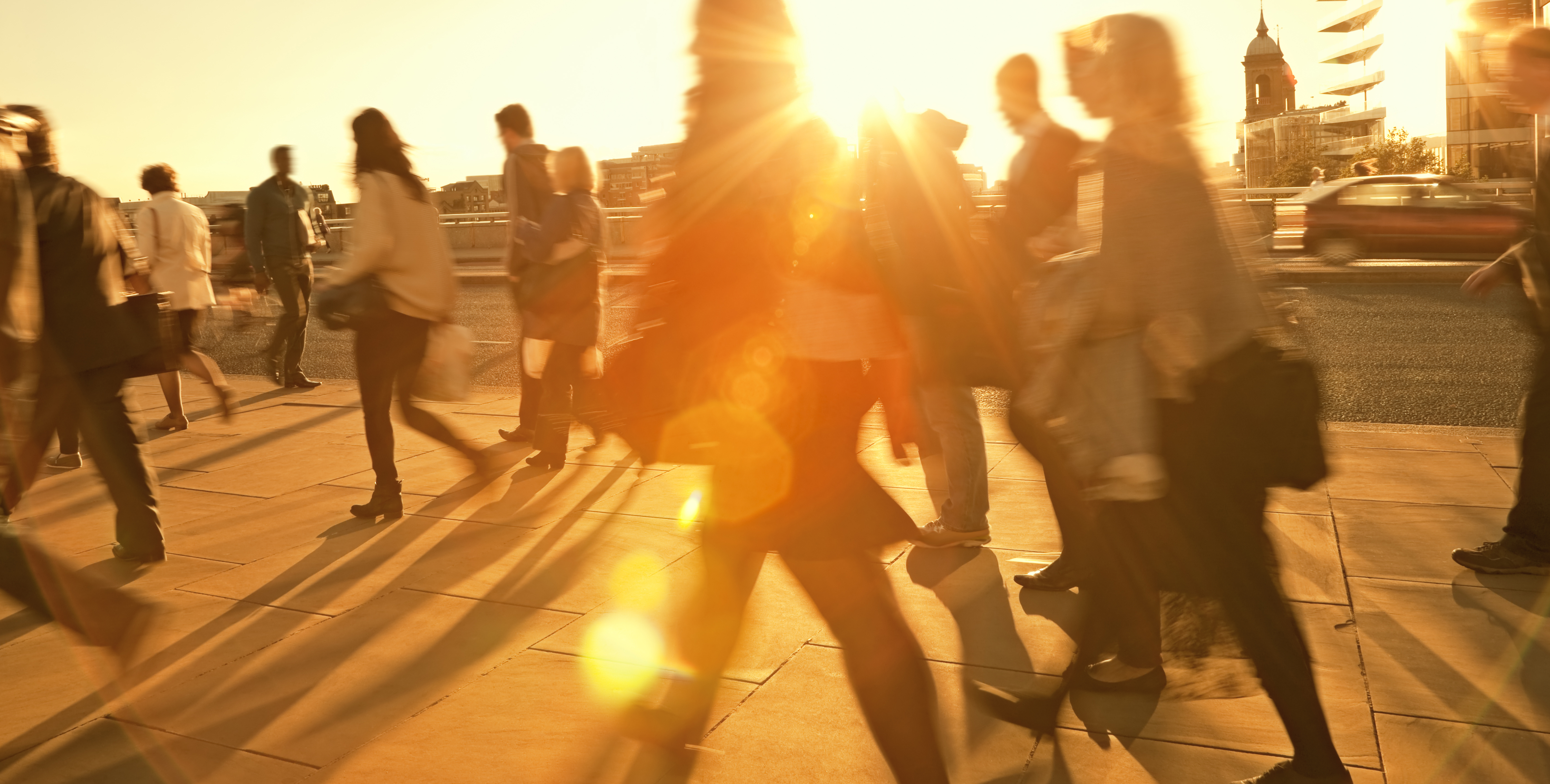Motion blurred photo of people walking backlit by the sun.