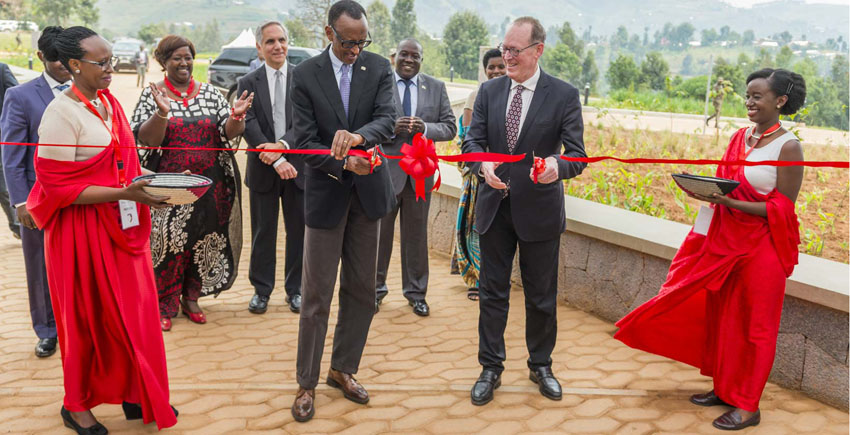 Two men cut a bright red celebratory ribbon with scissors