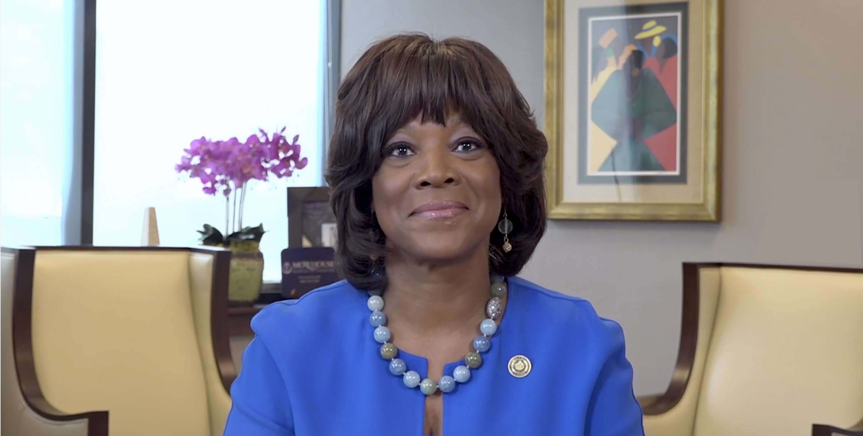 Image of Dr. Rice, wearing a blue suit, seated at a desk in her office