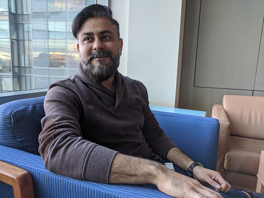 Portrait photo of young bearded man sitting in armchair in front of a window