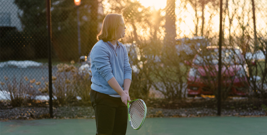 Silhouette of a male teen with Down syndrome holding a tennis racket