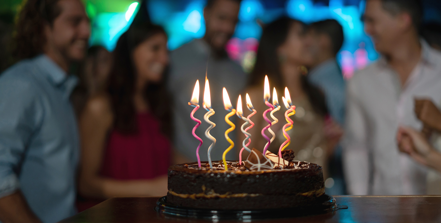 Close-up on a candle-lit cake on a table at a birthday party 