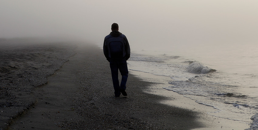 photo with silhouette of person walking on a foggy beach