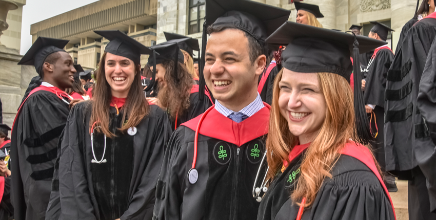 Smiling group of graduates on the steps of the Quad