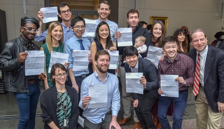 Group of students smiling and holding up their Match Day letters