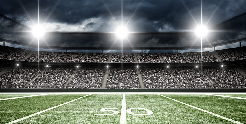 football stadium showing 50 yard line, crowd in seats and lights