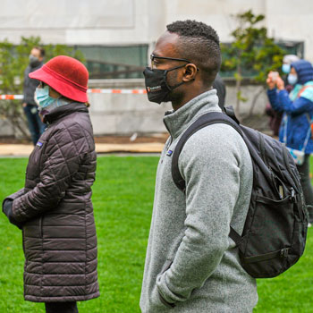 Rally participants standing on the Quad listeing