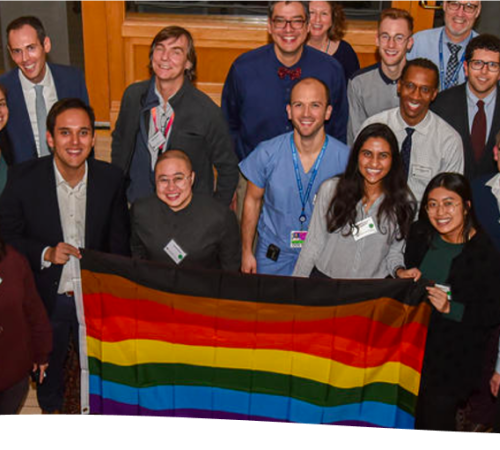 group of people holding an LGBTQ rainbow flag