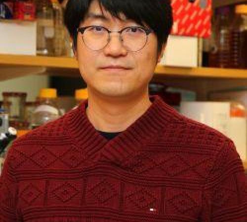 Head shot of a young Korean man in glasses with bangs swept to one side