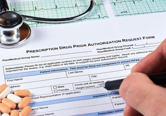 Photo of hand filling out a form, labeled "Prescription Drug Prior Authorization Form."