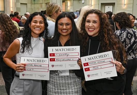 Three grinning students with long hair hold signs that say "I Matched!" with details of where they will pursue their residency training