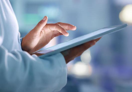 Health care professional wearing a white coat uses a tablet