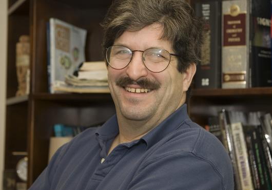 Head shot of a smiling man in front of a bookcase