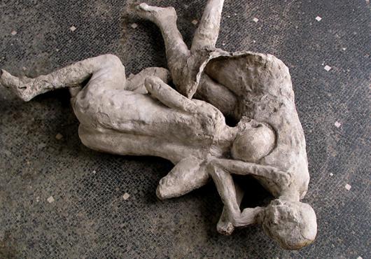 Plaster casts of two figures entangled on a tile floor
