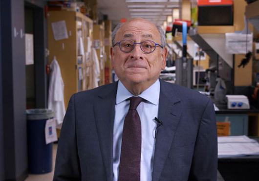 Stuart Orkin, standing in a laboratory wearing a suit, looks into the camera with a slight smile