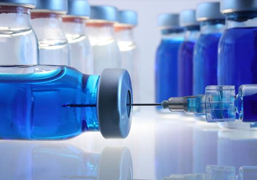 A close-up of glass containers with liquid medication and a syringe