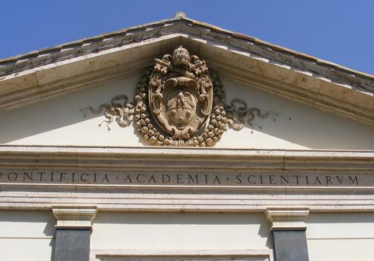 The front of a marble building has an intricate carved seal and the words "Pontificia Academia Scientiarum"