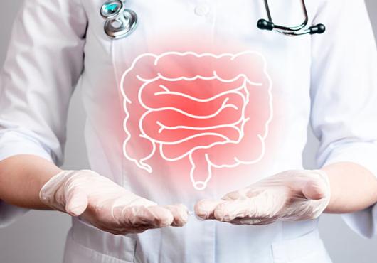 A human figure in a white coat, gloves, and stethoscope points to inflamed colon