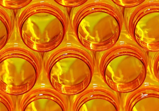 A stack of open orange prescription medicine bottles, glowing with backlight and lightning-shaped highlights.