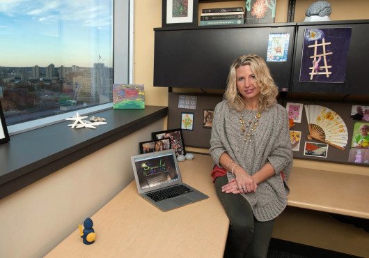 A woman sits at a desk overlooking the Boston skyline