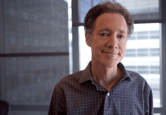 Portrait photo of Bruce Yankner in an office with window shades partially lowered