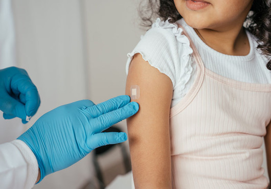 A doctor putting a bandaid on a young girl's arm.