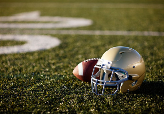 A football helmet and football on an empty field.