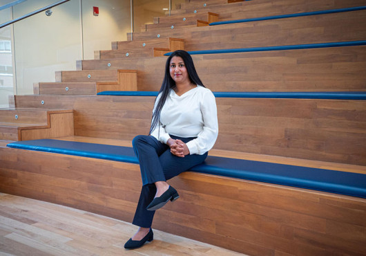 Photo portrait of Arya Rao sitting on a bench in an amphitheater.