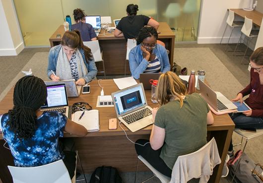 seven students studying at two desks in new student study center