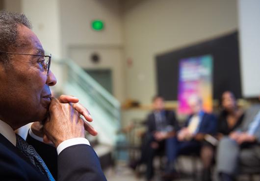 Poussaint looking on with panelists blurred in background