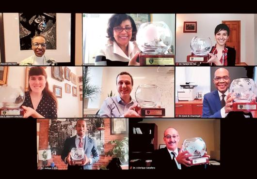 : Portraits of eight people smiling, with seven award winners holding commemorative crystal bowls. 