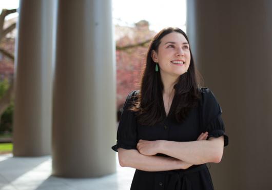 Alyssa Botelho, shot from the waist up in front of columns, looks off into the distance