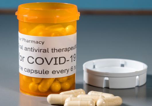 Image of a pill bottle that says COVID Rx with some pills near it