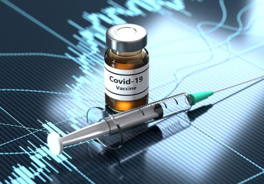 Photo illustration of a syringe and a bottle marked "COVID vaccine" 