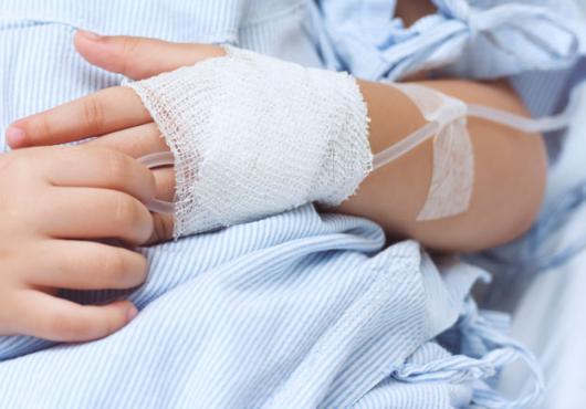 close up shot of a child's hands, one with an IV inserted 