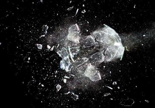 A piece of glass being destroyed against a black background