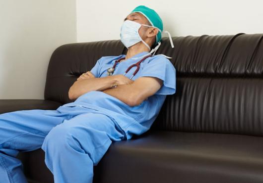 Doctor in blue scrubs dozing on a couch