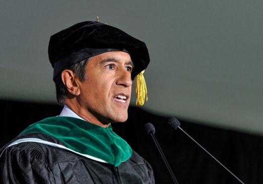 Photo of Sanjay Gupta in cap and gown delivering keynote address.
