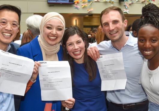 A group of 3 HMS medical students and two of their friends celebrate showing their Match Day letters. Image: Steve Lipofsky