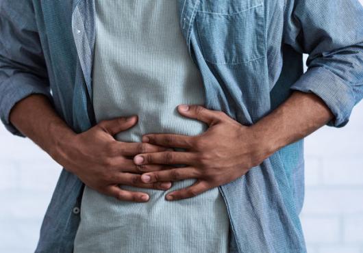 The torso of a person in a blue shirt with their hands over their stomach