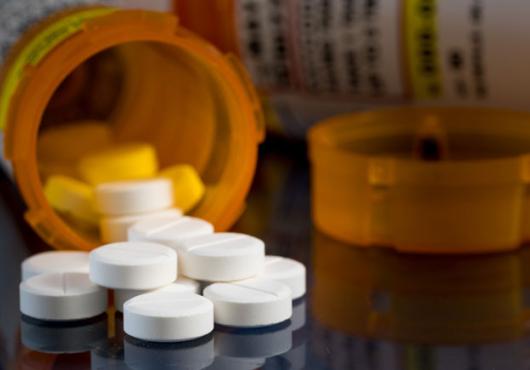 White pills spilling out of a prescription bottle 