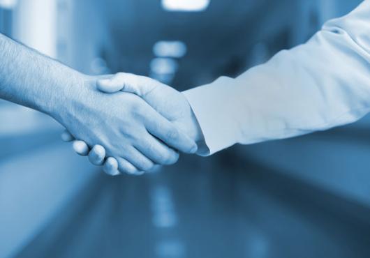 Photo illustration of two health care providers shaking hands in hospital hallway