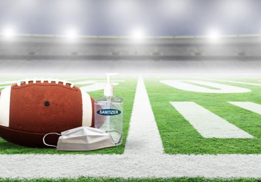 Photo of a football field with a ball, mask and sanitizer