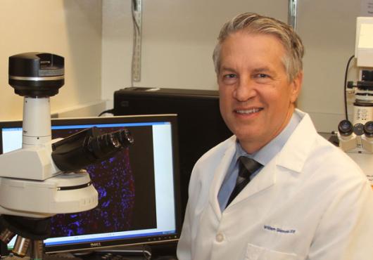 Photo of Giannobile in white lab coat at a microscope